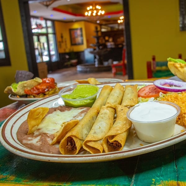 La Morena's Mexican platter with taquitos, refried beans, rice, guacamole, and sour cream.
