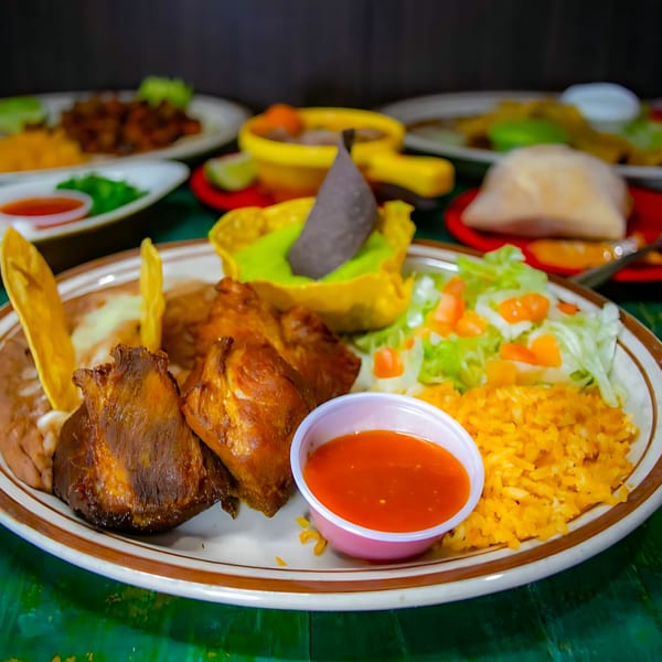La Morena's Mexican platter with roasted meat, rice, beans, salad, and a side of red sauce.